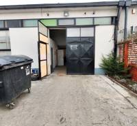 An industrial gate leads to the Warehouses and Halls in Trenčín. There is a garbage bin outside.
