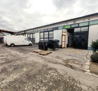 In the yard in Trenčín, there are industrial warehouses and halls with a vehicle.
