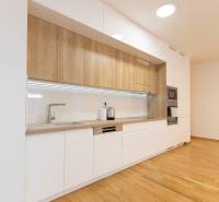 A kitchen in a 3-room apartment with a wooden decor floor and white cabinets.