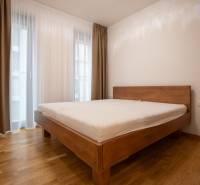 A bedroom with a bed and a wooden decor floor in a 3-room apartment.