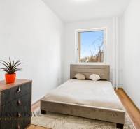 Bedroom in a 3-room apartment with a light bed and a cabinet with a wood-patterned floor.
