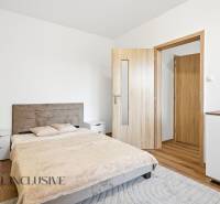 A bedroom in a 3-room apartment with a wooden decor floor, a double bed, and a dresser.