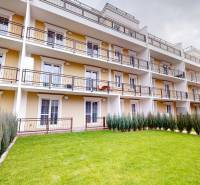 The exterior of an apartment complex with a garden and balconies of 2-room apartments in Komárno.