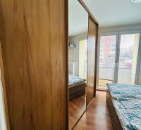 A bedroom in a 3-room apartment with a wooden decor floor and a large built-in wardrobe.