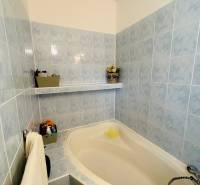 Bathroom with a bathtub with blue tiles in a 3-room apartment, decorations and a towel on the wall.