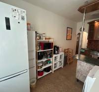 The kitchen in the 3-room apartment includes a white refrigerator, shelves, and a counter.