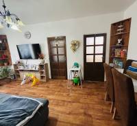 Living room with a sofa, wooden decor flooring, a television, and children's toys in a three-room apartment.