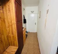 A narrow hallway with wooden furniture and white walls in a 3-room apartment.