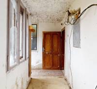 A hallway in a family house with white walls and wooden doors, visible are electrical cables.