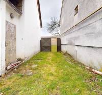 A family house in Vieska in Dojč with a gate, grassy yard by the walls.