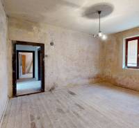 A room in a family house with raw walls and a floor with a wood decor.