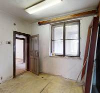 A room in a family house with a window, wooden paneling, and empty walls.