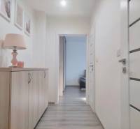 A hallway in a 2-room apartment with a chest of drawers, a lamp, and a wooden decor floor.