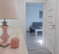 Interior of a 2-room apartment with a view of a gray sofa and a floor with a wooden decor.