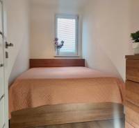 A bedroom in a two-room apartment with a bed and a spacious wooden dresser.