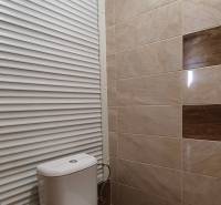 Bathroom with toilet and beige tiles in a 2-room apartment.
