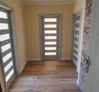 A hallway in a 2-room apartment with a wooden decor floor and light-colored doors.
