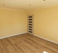 A bright room with a wooden decor floor and a door in a two-room apartment.