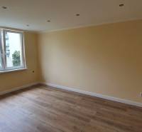 A room with yellow walls and a wooden decor floor in a two-room apartment.