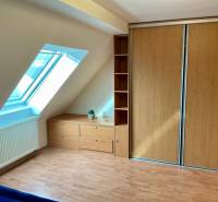 Attic room with a window, cabinet, built-in wardrobe, and floor with a wooden decor.