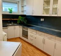 A kitchen in a 3-room apartment with white cabinets and a wood-patterned floor.