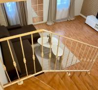 A living room with wood-patterned flooring, a brown sofa, and a television in a three-room apartment.