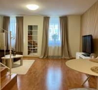 Living room in a 3-room apartment with a TV, sofa, table, and floor with a wooden decor.