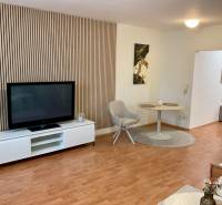 Living room in a 3-room apartment with a TV, armchair, table, and floor with a wooden decor.