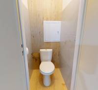 A toilet with a wooden decor floor in a 3-room apartment.