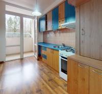 A kitchen in a 3-room apartment with a balcony and a floor with a wood decor.