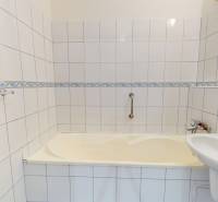 A bathroom with white tiles and a bathtub in a 3-room apartment.