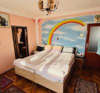 Bedroom in a family house with a rainbow painting on the wall and a wooden decor floor.