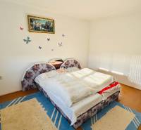 A bedroom in a family house with a wood-patterned floor and an upholstered bed.