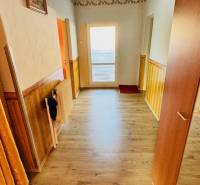 A hallway in a family house with a wooden decor floor and a decorated ceiling.
