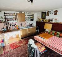 A kitchen in a family house with a carpet, wooden cabinets, and a dining table.