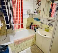A bathroom in a family house with a bathtub, a sink, shelves, and colorful towels.