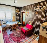 A kitchen in a family house with a living room, an armchair, a carpet, a dining table, and decorations.