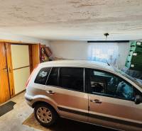 A garage in a family house with a car, boxes, and wooden doors.