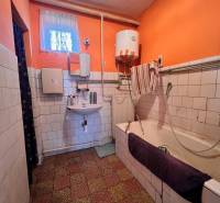 A bathroom in a family house with orange walls and older furnishings.