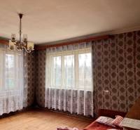 A room in a family house with wallpaper, a chandelier, and a wooden decor floor.