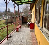 Terrace with paving of a family house in Komjatice, with a garden view and a bench.