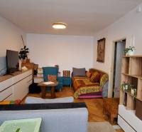 A living room in a 3-room apartment with a wooden decor floor, colorful sofas, and furniture.