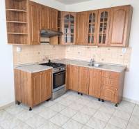 A kitchen in a 3-room apartment with light tiles and wooden cabinets.