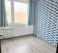 A room with wallpaper featuring a whale pattern, floor with a wooden decor.