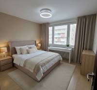 A bedroom in a 3-room apartment with carpet flooring and muted brown tones.