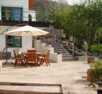 The terrace of a family house in Hainburg an der Donau with wooden furniture and a sunshade.