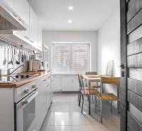 A kitchen in a 3-room apartment with white cabinets and a dining table by the window.