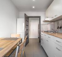 Kitchen in a 3-room apartment with white cabinets, wooden table, and storage space.