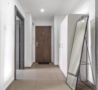 A hallway in a 3-room apartment with tiles, a standing mirror, and white cabinets.