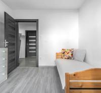 A room in a 3-room apartment with a bed, a dresser, and a floor with a wood decor.